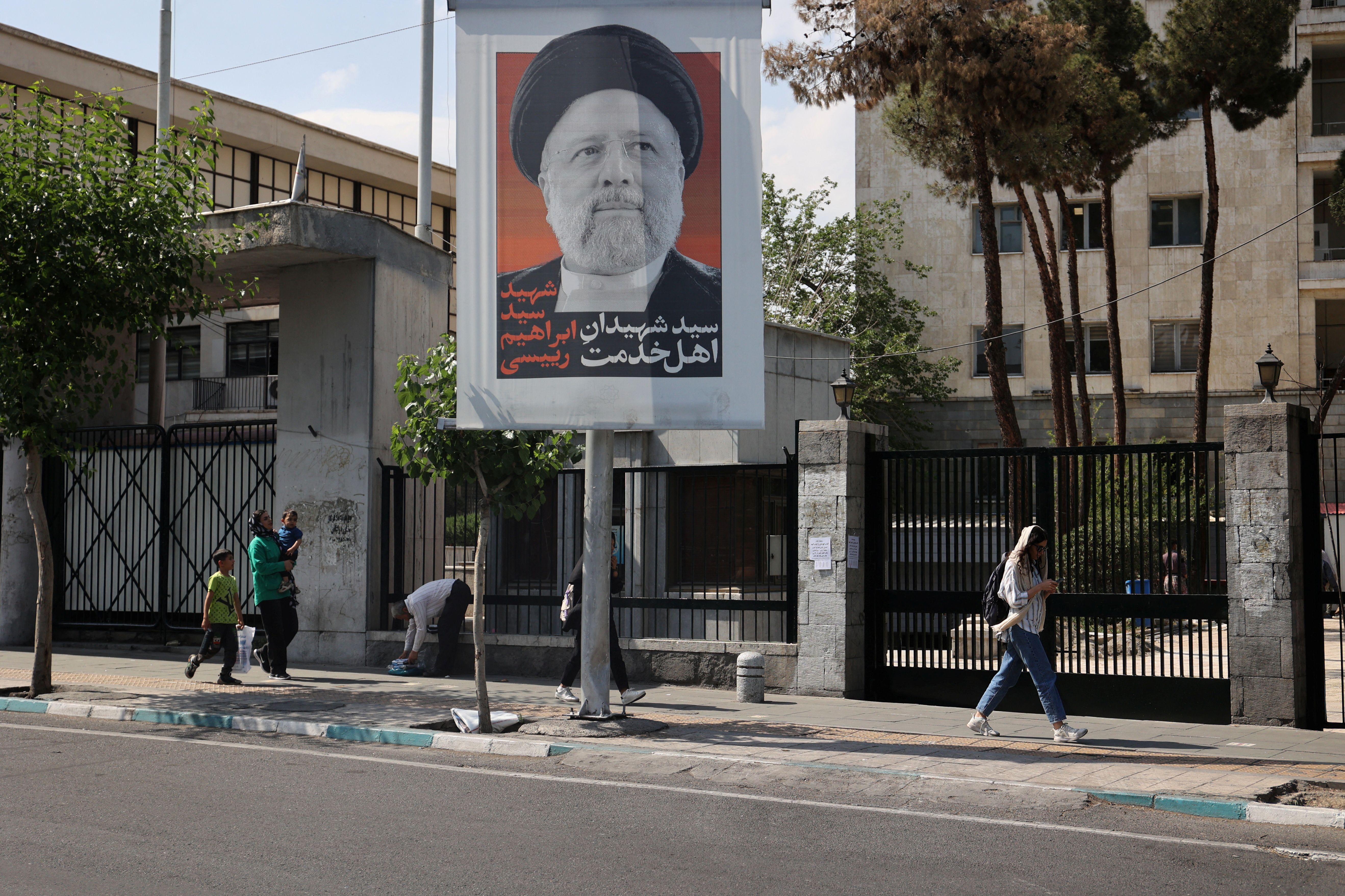 A woman walking past a banner of Iranian President Ebrahim Raisi in Tehran, May 2024 