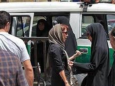 A hijab police patrol with black-cladded agents stopping women in the street to demand a full headscarf