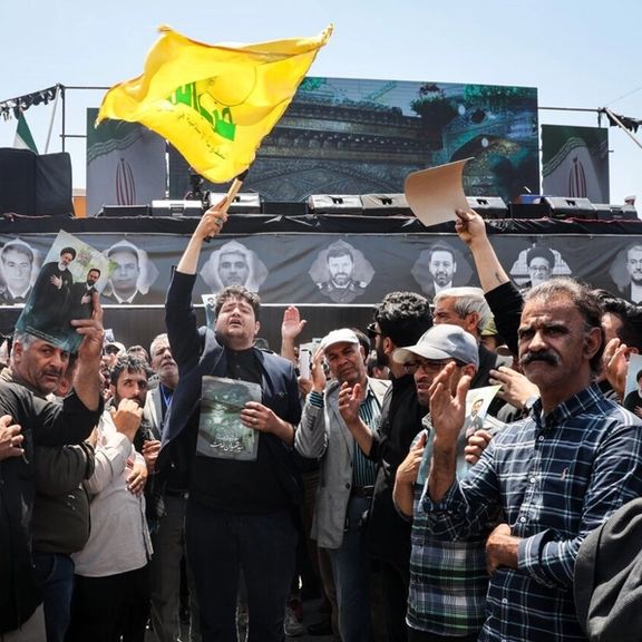 یکی از حاضران در مراسم تشییع رئیسی در حال تکان دادن پرچم حزبالله، مشهد، سوم خرداد
