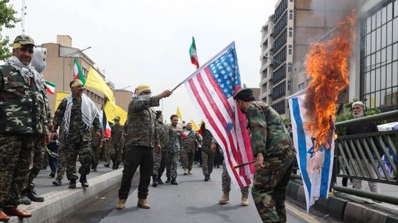 Men in military uniforms setting fire to Israeli and US flags in Tehran. April 29, 2022