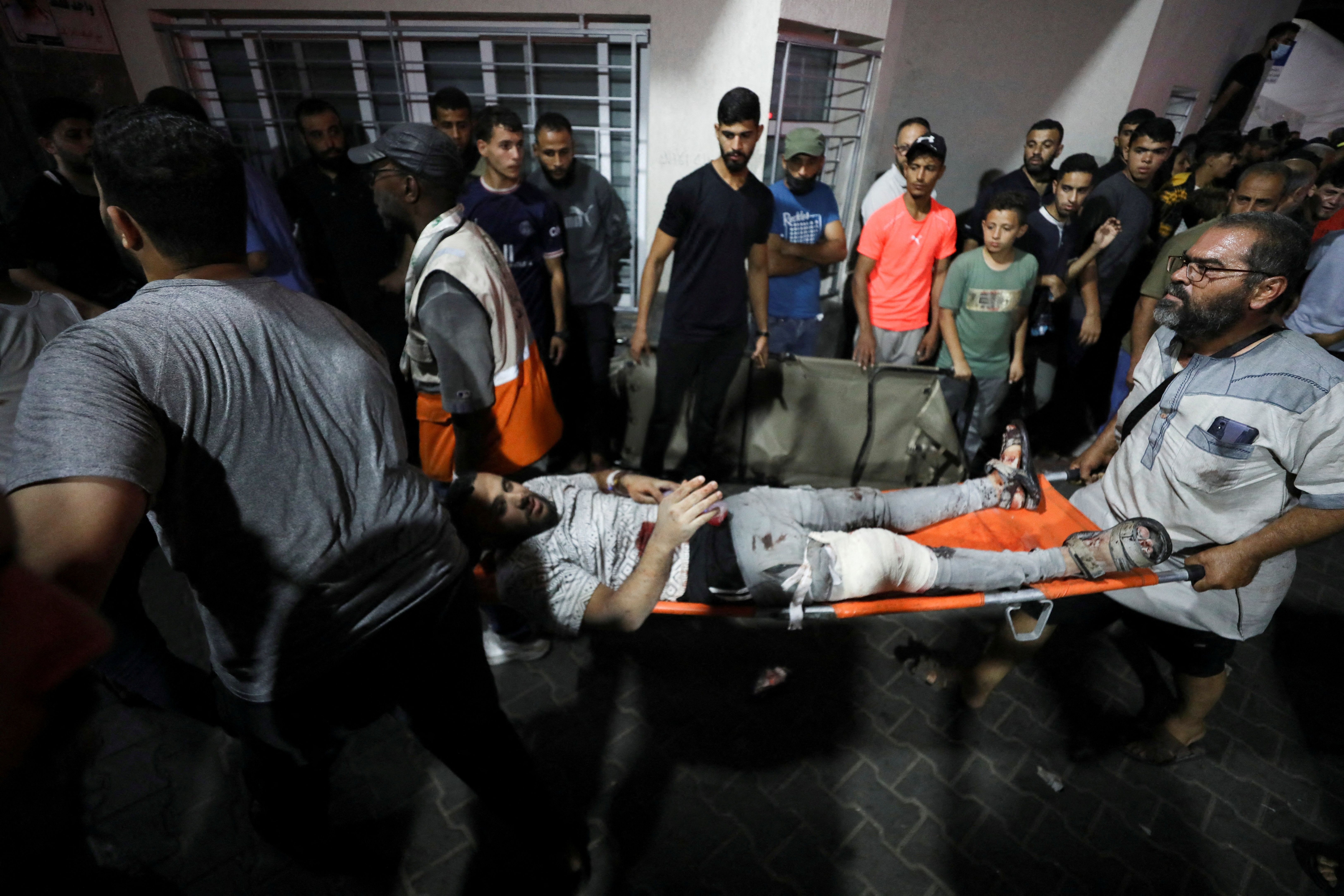 An injured person is assisted after an Israeli air strike hit At Al-Ahli Hospital, according to Gaza Health Ministry in Gaza City, Gaza Strip, October 17, 2023.