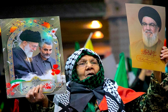 Iranian woman holds up images of slain Hezbollah leader Hassan Nasrallah, and Supreme Leader Ali Khamenei alongside assassinated IRGC commander Qasem Soleimani