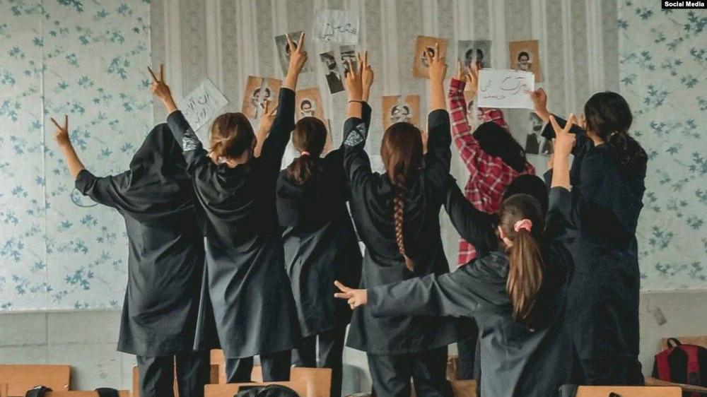 A group of schoolgirls unveiling in their classroom after tearing photos of the founder of the Islamic Republic Ruhollah Khomeini  
