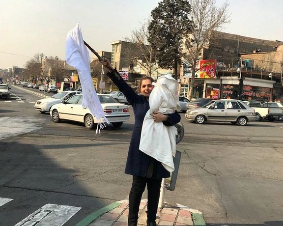A woman in Iran removes her veil in defiance of police