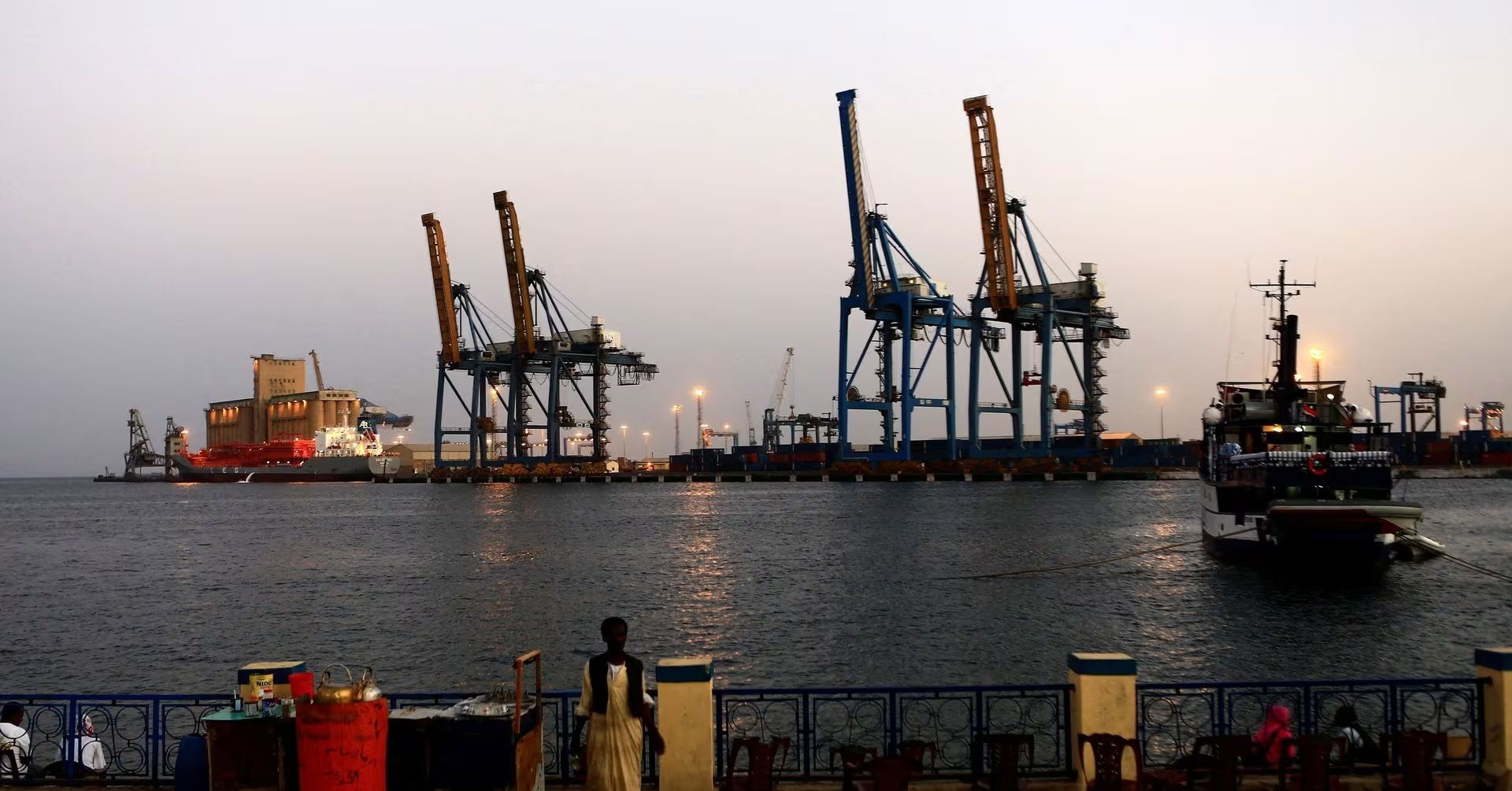 A man stands opposite the modern port at the harbour in Port Sudan at Red Sea State February 24, 2014. 