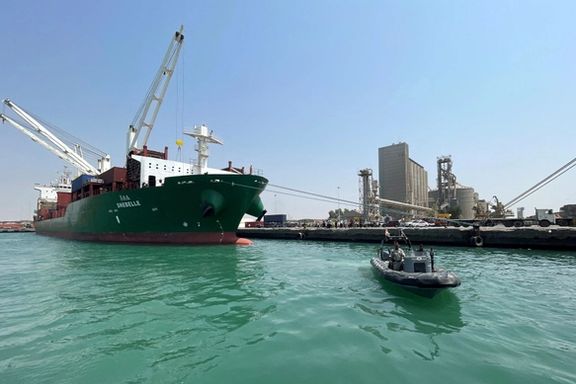 A coastguard boat sails past a commercial container ship docked at the Houthi-held Red Sea port of Hudaydah.