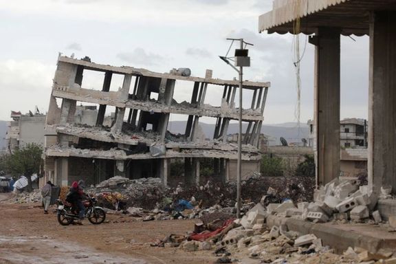 People ride a motorbike past buildings damaged by an earthquake that hit Syria on February 6, in the rebel-held town of Jandaris, Syria March 29, 2023.