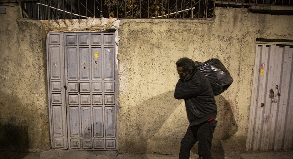 A poor man in Iran collecting items from garbage bins to make a living. Undated