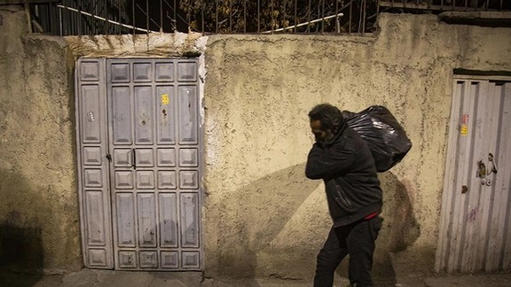 A poor man in Iran collecting items from garbage bins to make a living. Undated