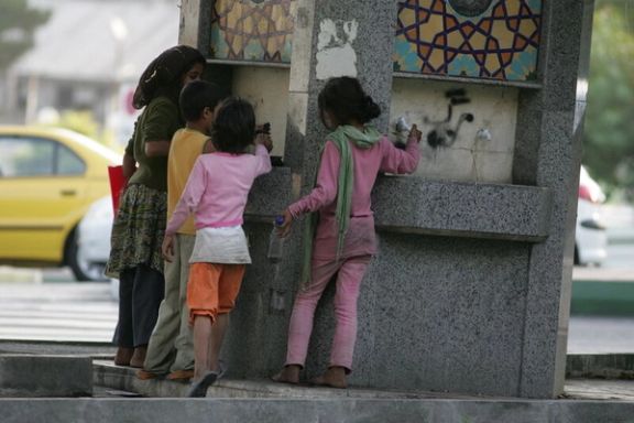A group of Afghan kids, gathered around a public water fountain in Iran
