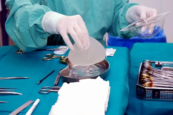 A surgeon preparing a silicone breast implant during a cosmetic surgery procedure