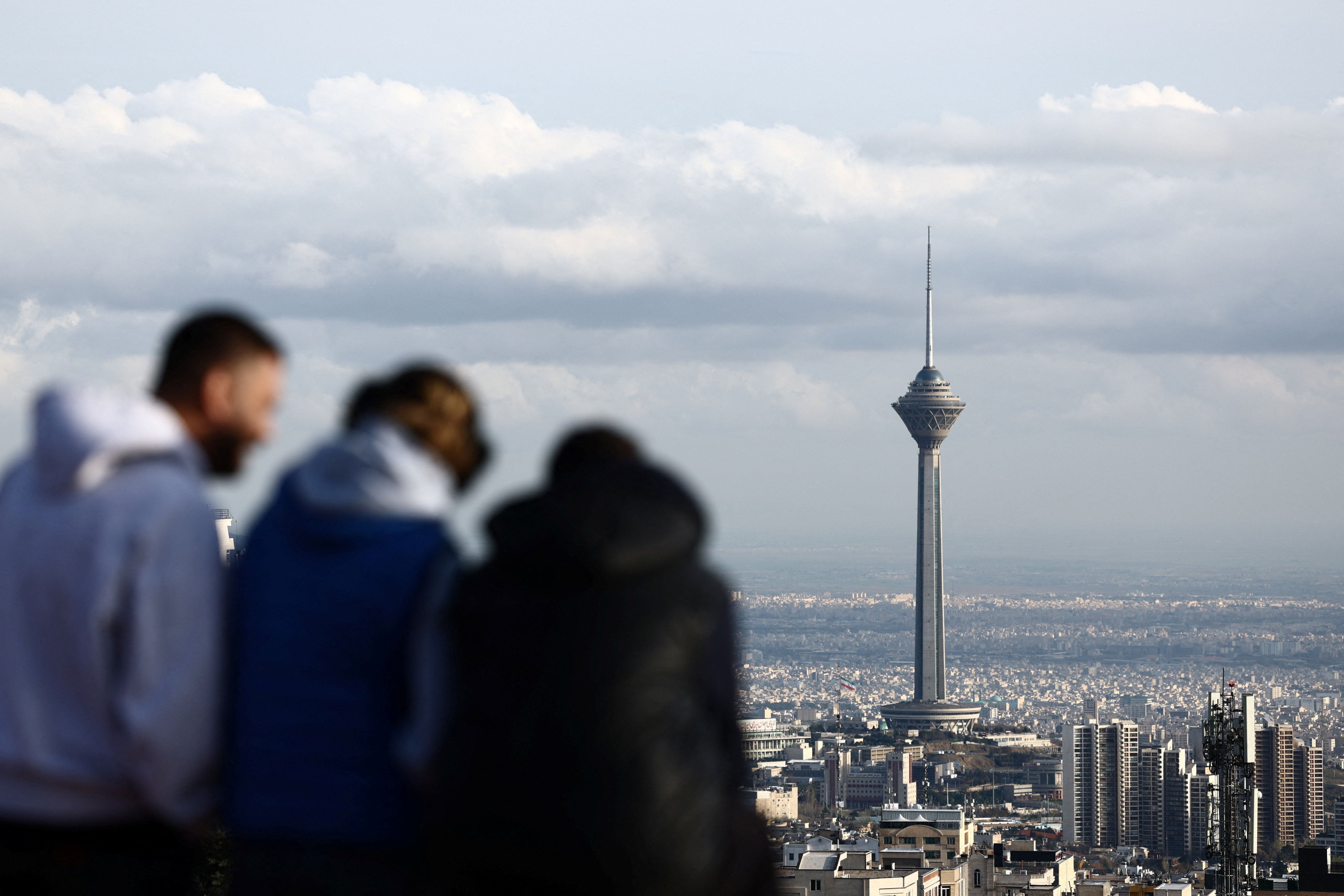 People stand at a park in view of Milad Tower, amid the US-Israeli conflict with Iran, in Tehran, Iran, March 25, 2026.