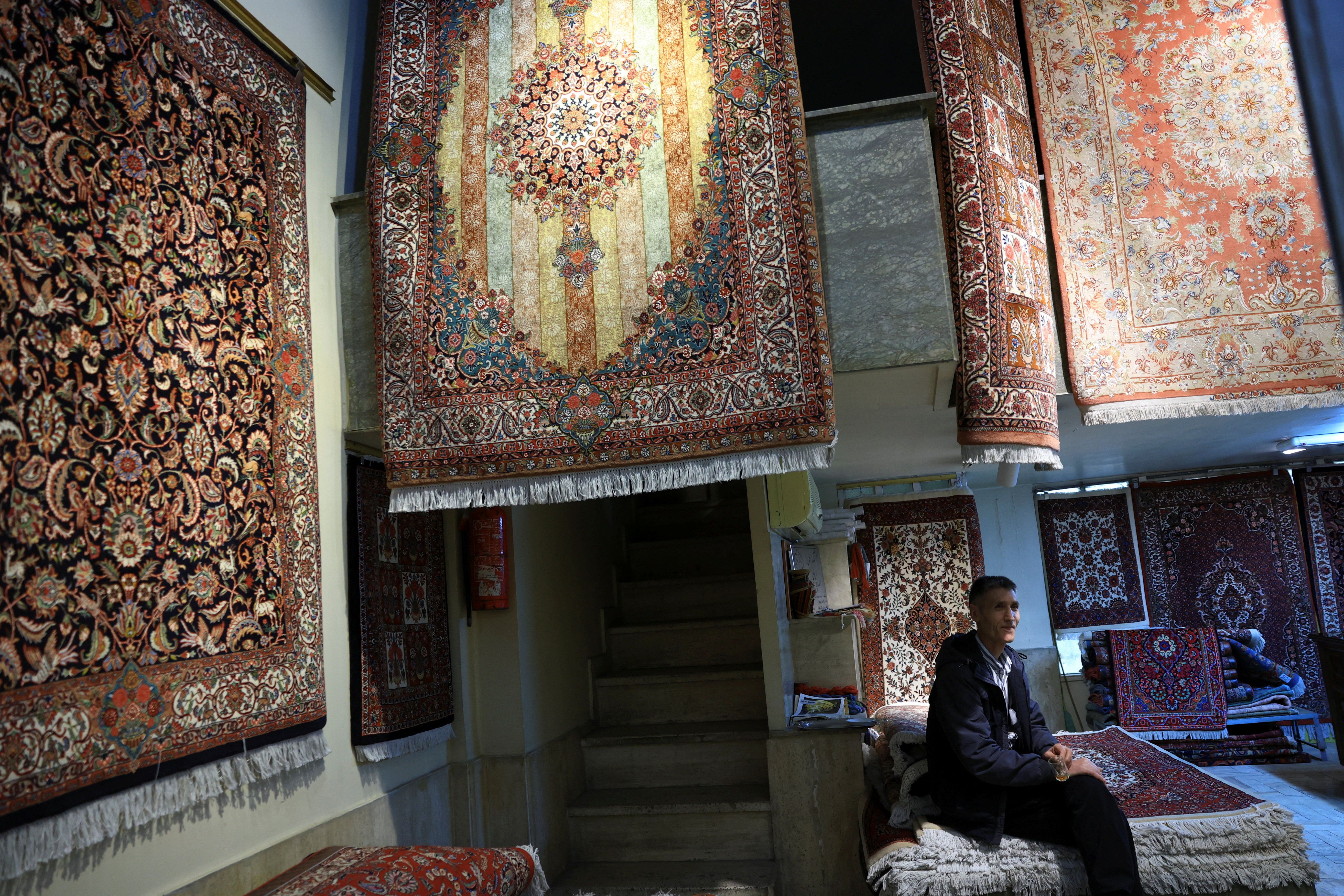 A vendor sits inside his shop selling hand-woven carpets at Tehran’s Grand Bazaar, Iran, April 13, 2026. 