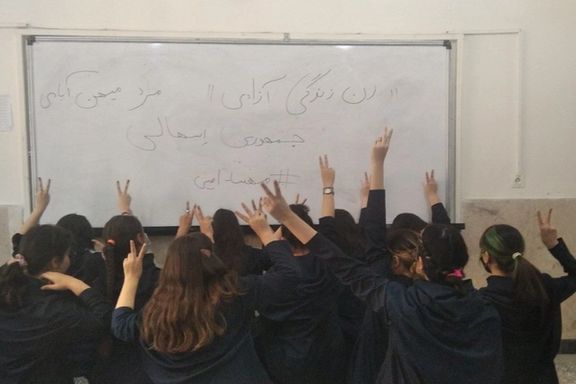 Several schoolgirls unveiling in their classroom in support of the Women, Life, Liberty movement