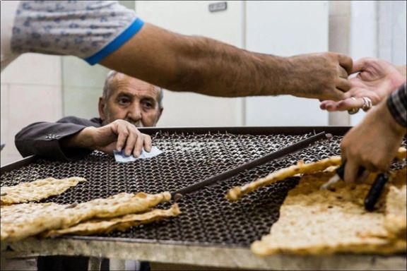A man waits his turn to buy fresh Sangak bread at a traditional bakery, Tehran, Iran, August 8, 2016