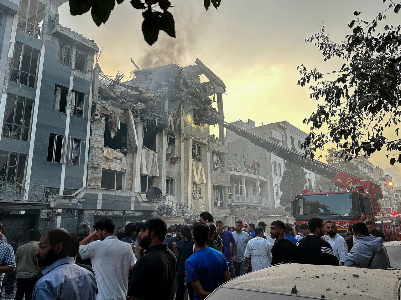People watch rescue workers near a building destroyed by an Israeli strike, Tehran, Iran, Jun 2025