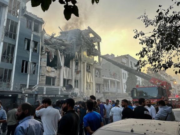 People watch rescue workers near a building destroyed by an Israeli strike, Tehran, Iran, Jun 2025