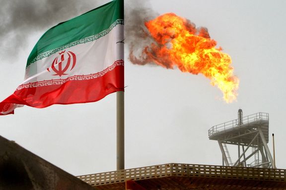 A gas flare on an oil production platform is seen alongside an Iranian flag in the Persian Gulf, July 25, 2005.