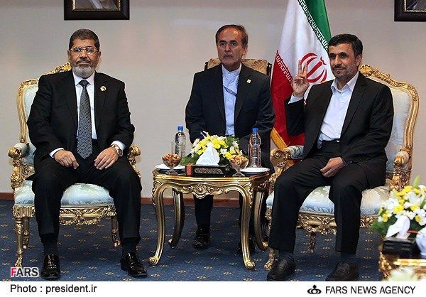 Former president of Iran Mahmoud Ahmadinejad (right) flashes a victory sign during a meeting with his Egyptian counterpart Mohammed Morsi (left) on the sidelines of the Non-Aligned Movement summit in Tehran, on August 30, 2012. 