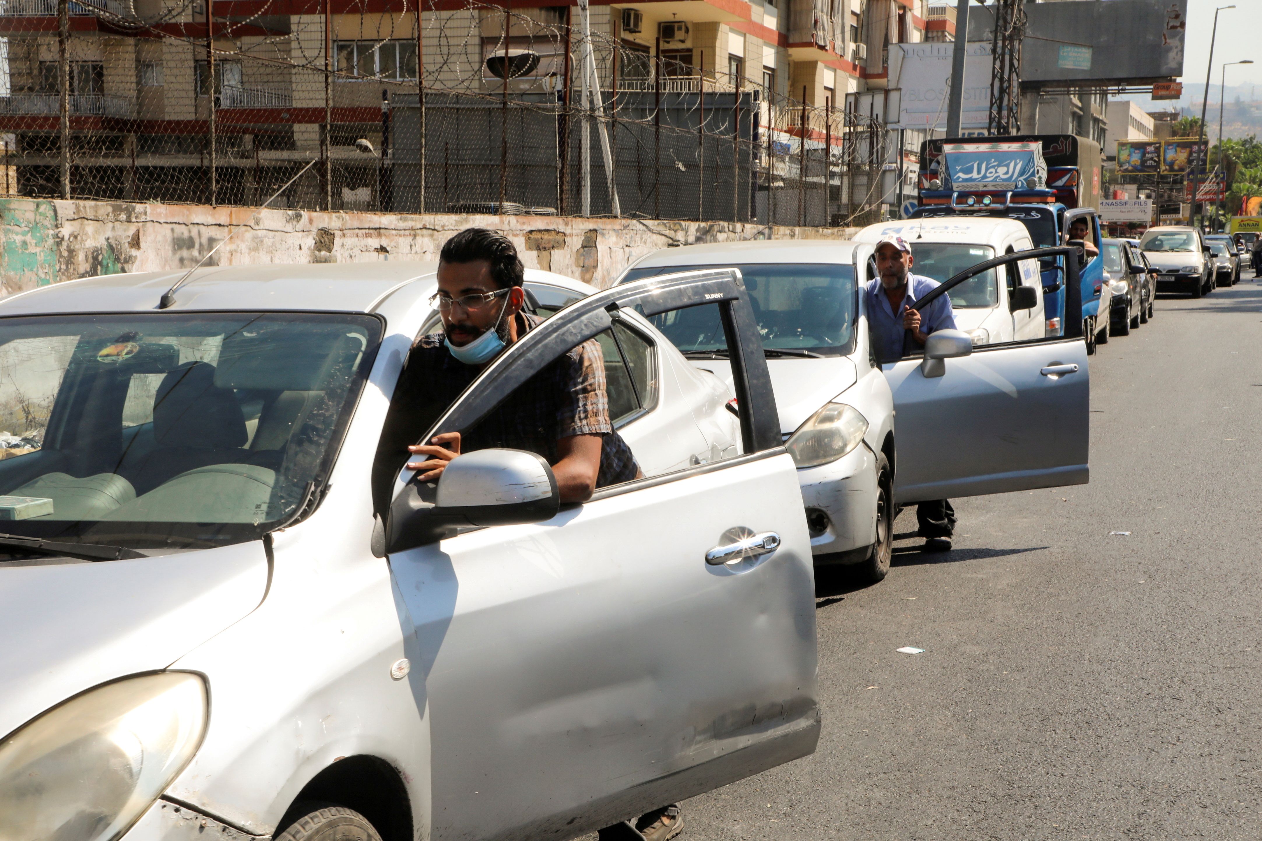 Several Iranians pushing their cars to a gas station 