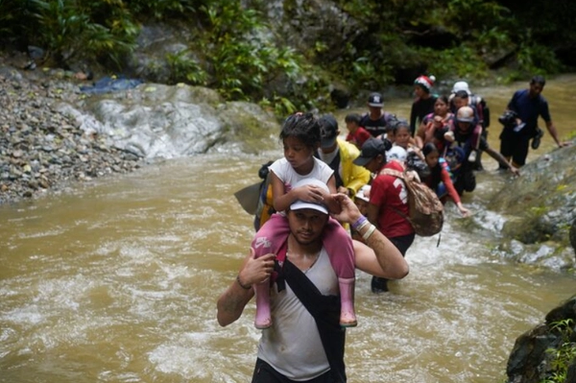 A migrant carries a child as they along with others continue their journey to the U.S. border, in Acandi, Colombia July 9, 2023. REUTERS/Adri Salido