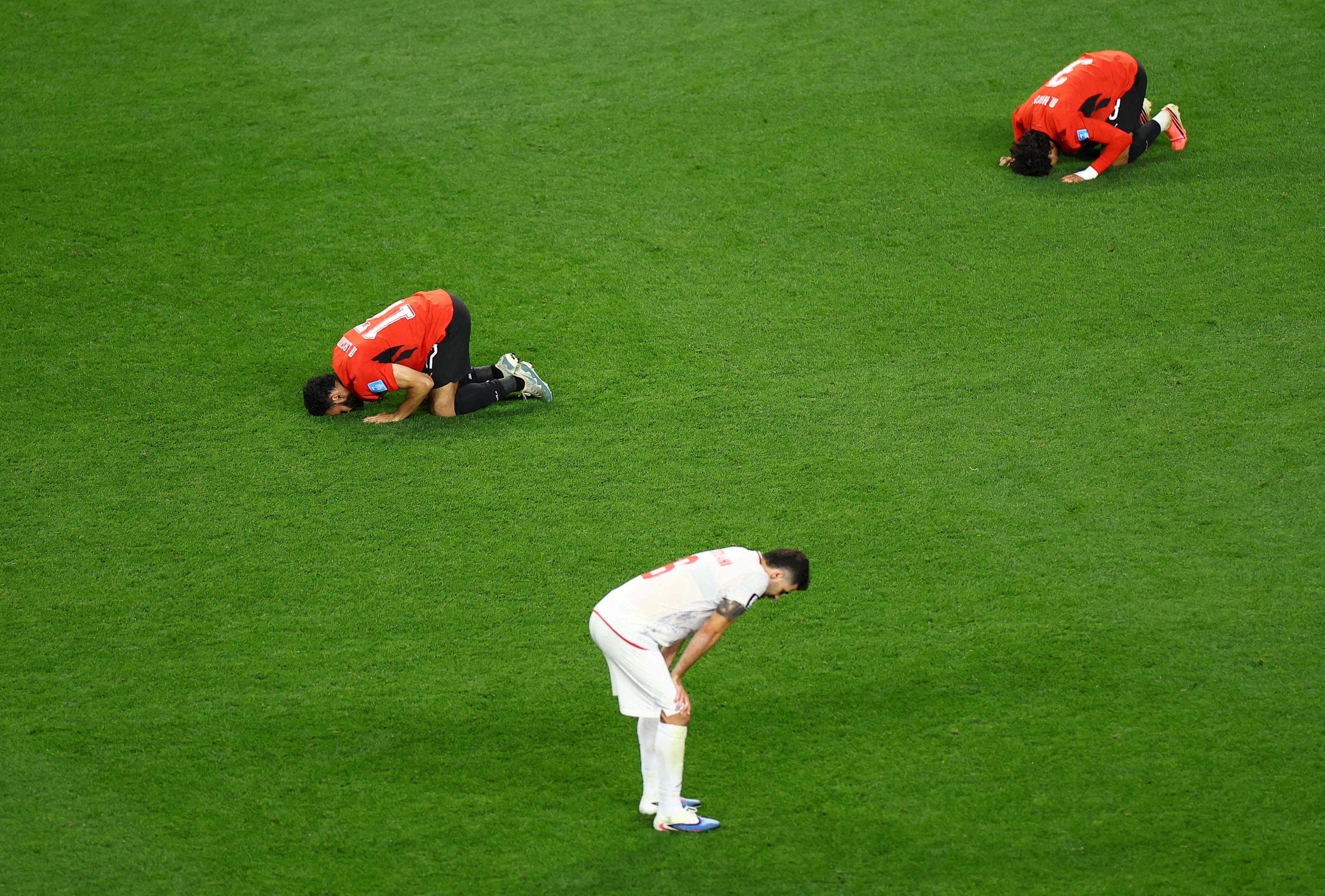 Egypt's Mohanad Lashin and Egypt's Mohamed Hany celebrate as Iran's Saeid Ezatolahi looks dejected after the match. 