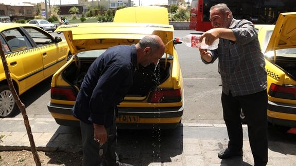 Iranian taxi drivers splash water on themselves to cool down during the heat surge in Tehran, August 2, 2023.