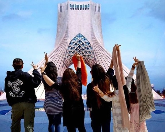 Several Iranian women remove their headscarves in front of Tehran’s iconic Azadi tower, formerly known as the Shahyad Tower.