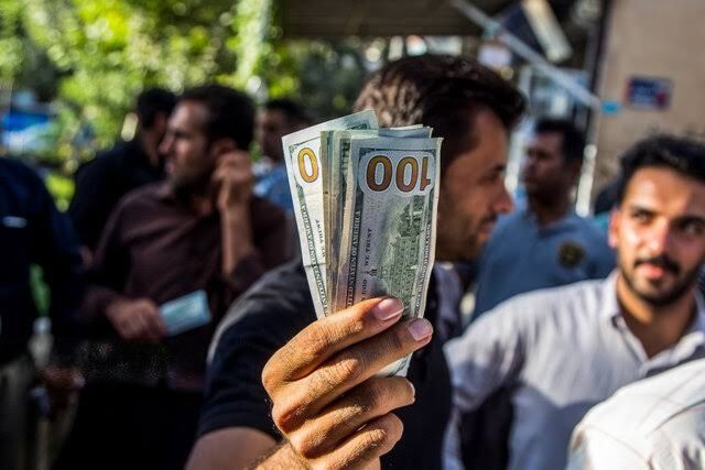 A man displays US dollar banknotes on a street in Tehran, Iran.