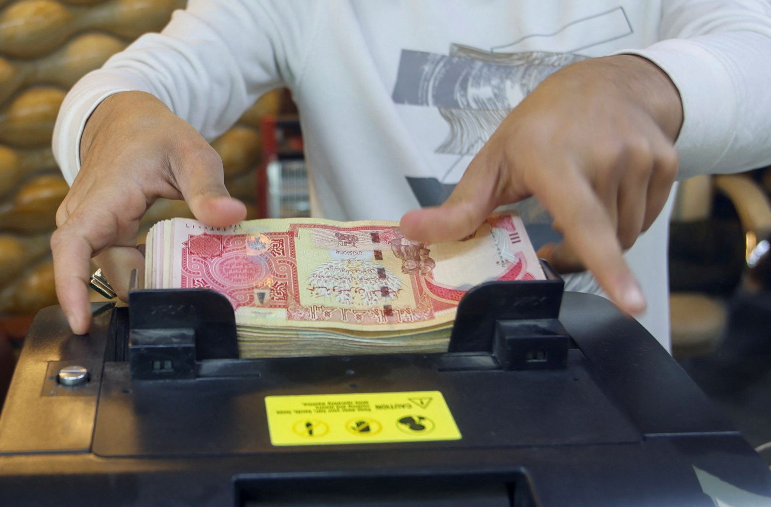  A man counts Iraqi dinars on a money counting machine at a currency exchange shop in Baghdad, Iraq, January 23, 2023.