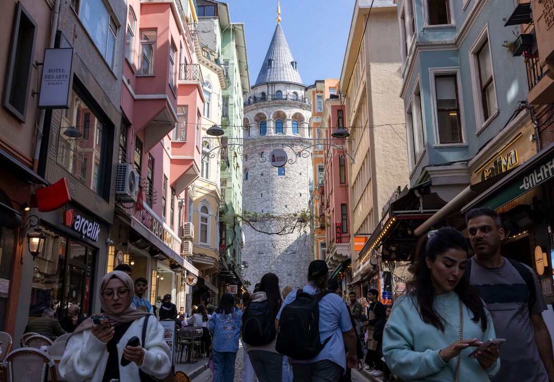 People walk on a small street that leads to the historical Galata Tower in Istanbul.
