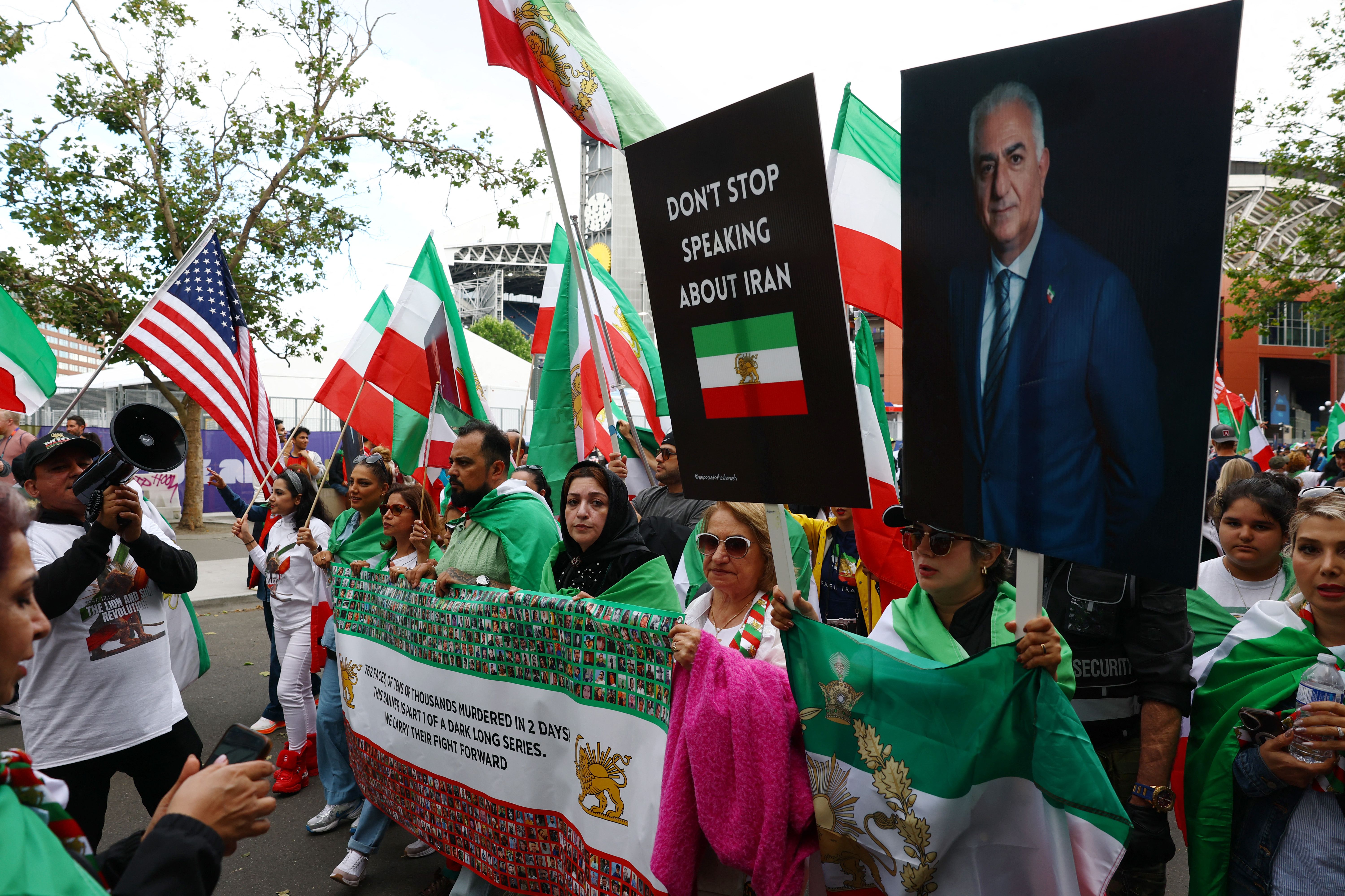 Iranian protesters display banners reading "don't stop speaking about Iran" and of former Crown Prince of Iran, Reza Pahlavi outside the venue of Iran-Egypt World Cup match in Seattle.