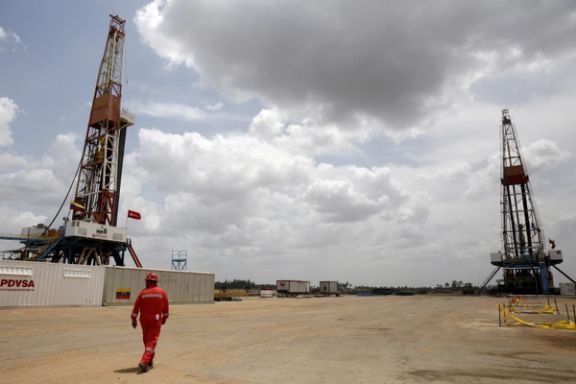 An oilfield worker walks next to drilling rigs at an oil well operated by Venezuela's state oil company PDVSA, in the oil-rich Orinoco belt, April 16, 2015.
