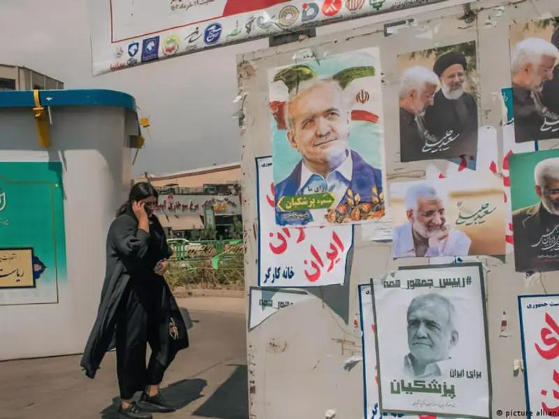 A woman walks past a wall covered with campaign posters for the upcoming presidential election runoff in Iran, featuring candidates Masoud Pezeshkian and Saeed Jalili.