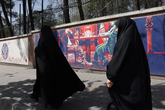 Two Iranian women walking past a mural against the negotiations with Washington, Tehran (April 2025)