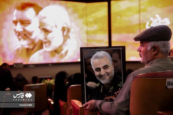 A man holding a photo of former IRGC-Quds Force commander Qasem Soleimani during a ceremony on the eve of his fourth death anniversary, Tehran, January 2, 2024