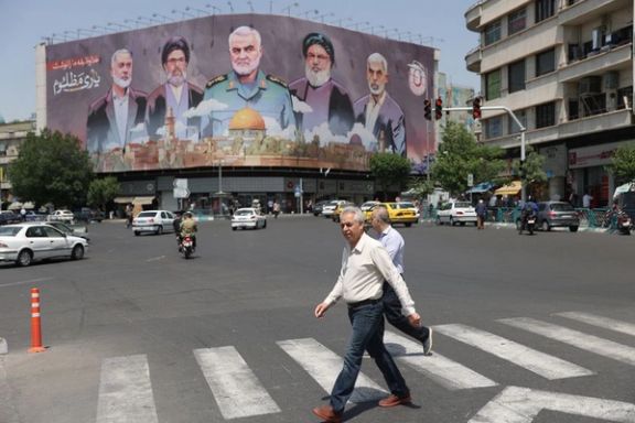 Pedestrians walk in front of a political baA street scene in Tehran