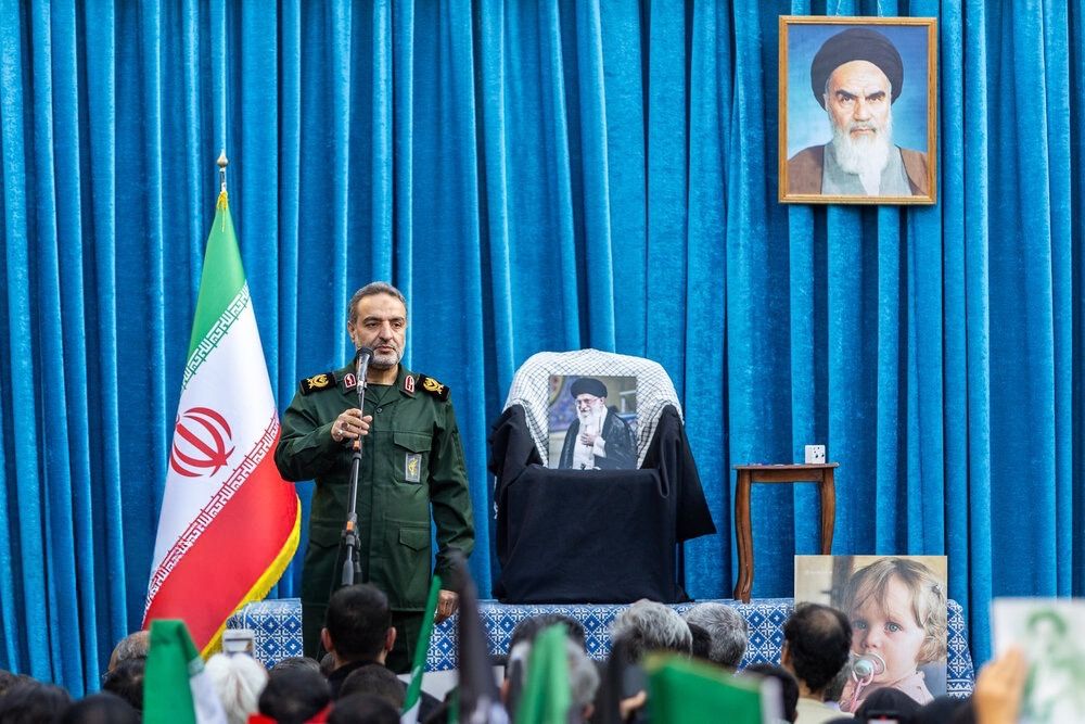 An IRGC commander speaks for a crowd gathering to honour the memory of Iran's slain supreme leader Ali Khamenei, with a picture of him resting on his seat, Tehran, May 7, 2026