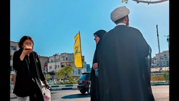 شابة إيرانية دون الحجاب الإجباري بجوار رجل تحت راية حزب الله