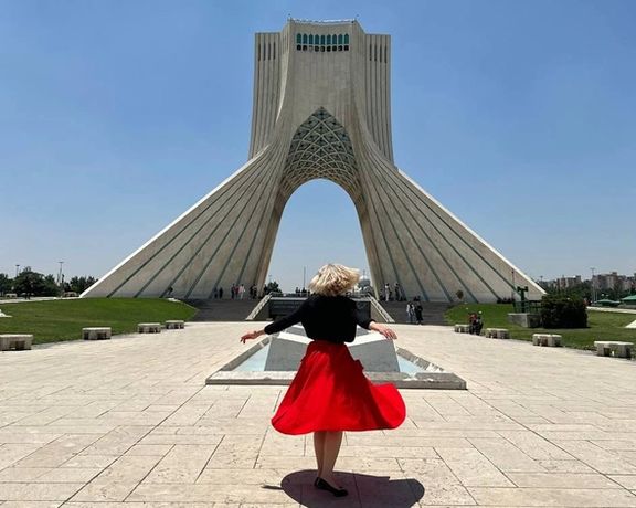 An Iranian woman without mandatory hijab in front of Tehran’s Azadi tower