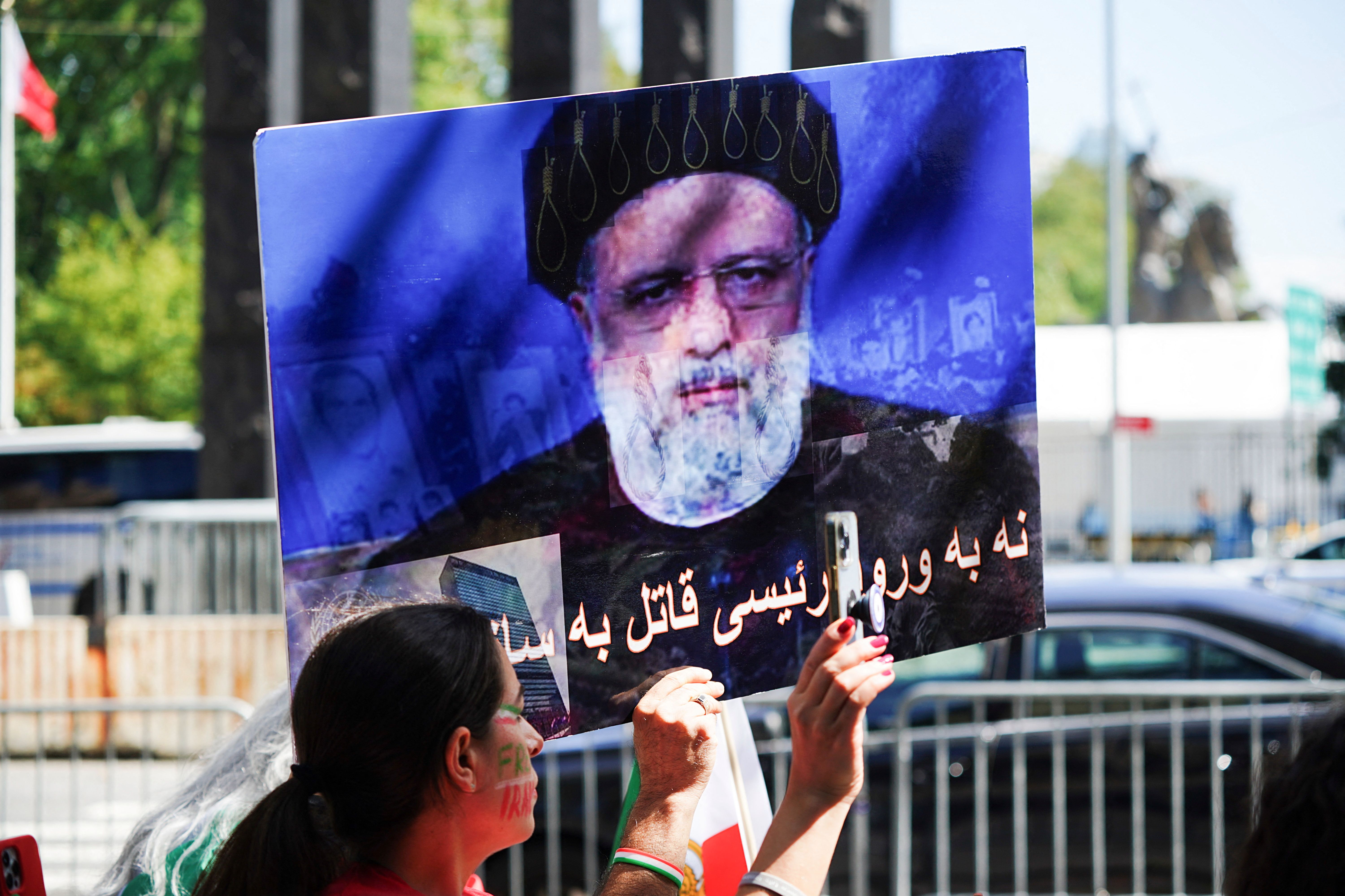A demonstrator holds a placard with the image of Iran's President Ebrahim Raisi as Iranian Americans protest near the United Nations headquarters during Raisi's visit to New York City, September 19, 2023. 