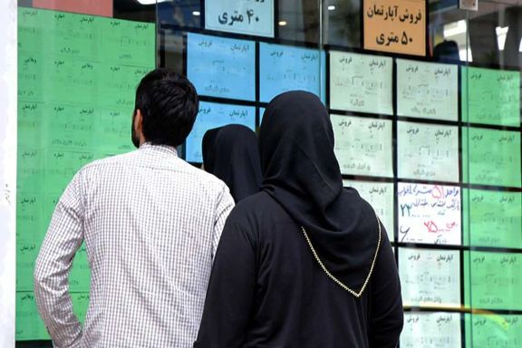 Several people looking at the ads on the door of a real estate agency in Tehran