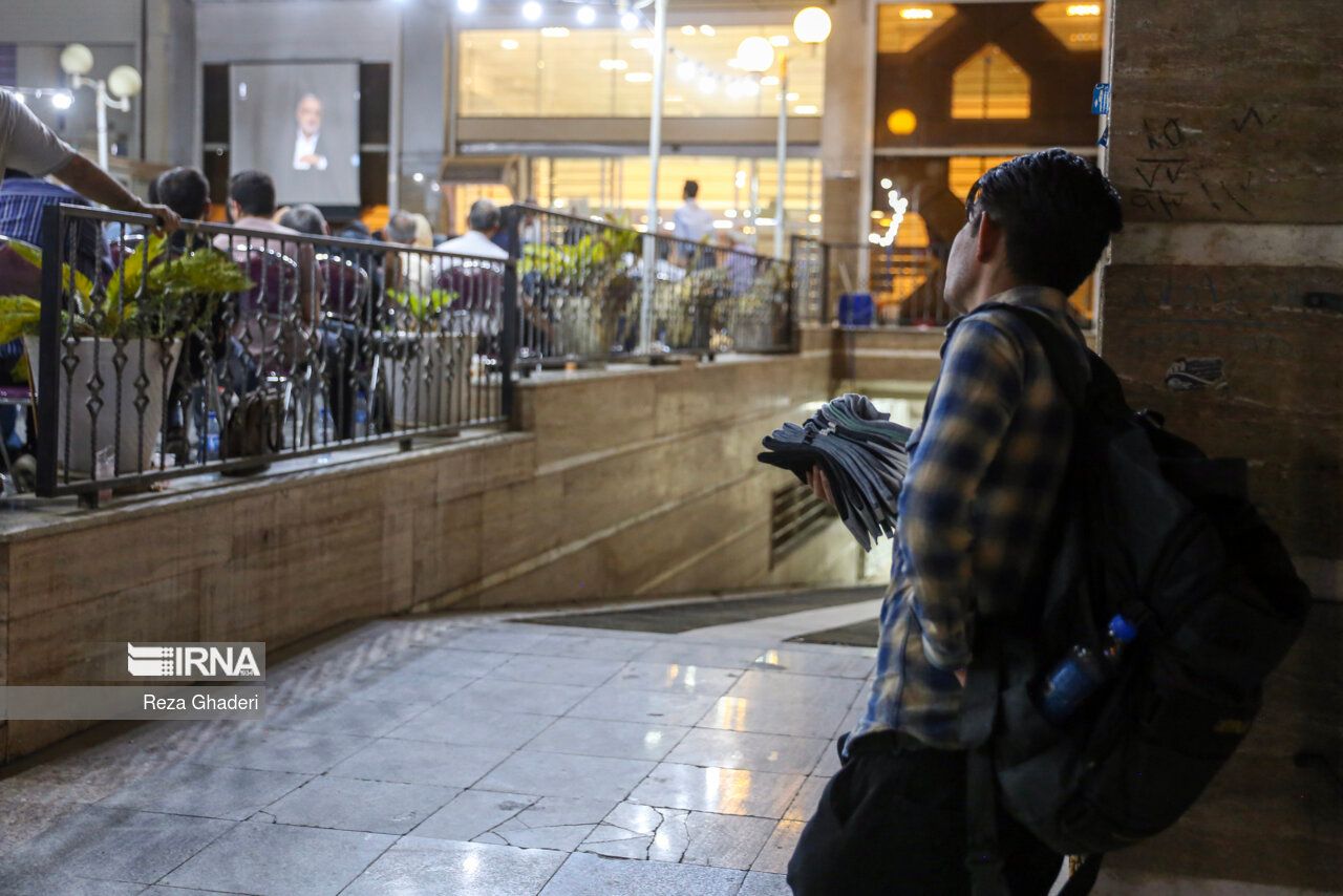 A street vendor looking at people watching a presidential debate in Shiraz (June 2024) 