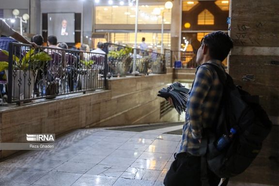 A street vendor looking at people watching a presidential debate in Shiraz (June 2024)