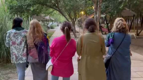 A group of women walking in a park without headscarves but still dressed conservatively