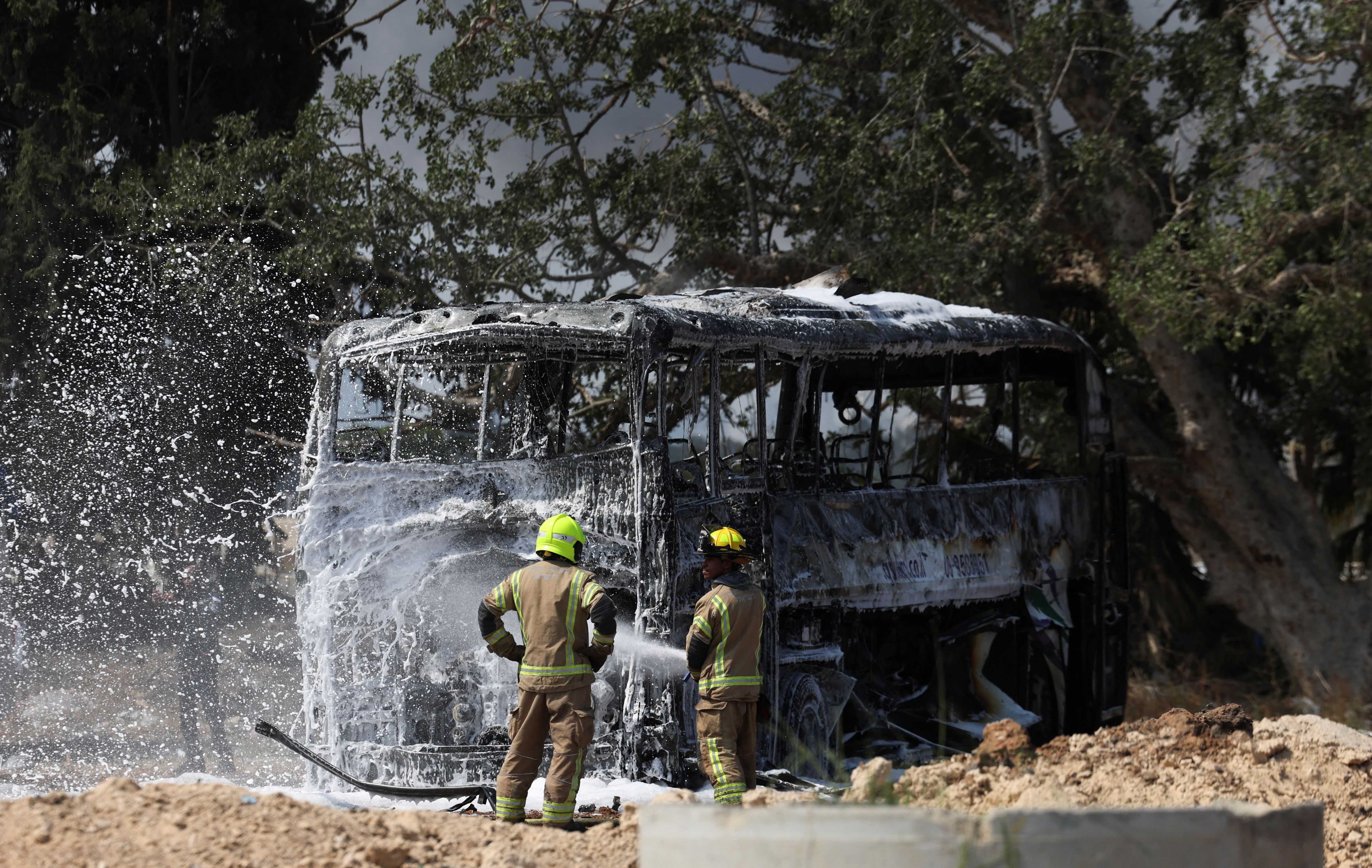 Firefighters work to extinguish a fire on a bus following a missile attack from Iran, in Herzliya, Israel, June 17, 2025. 
