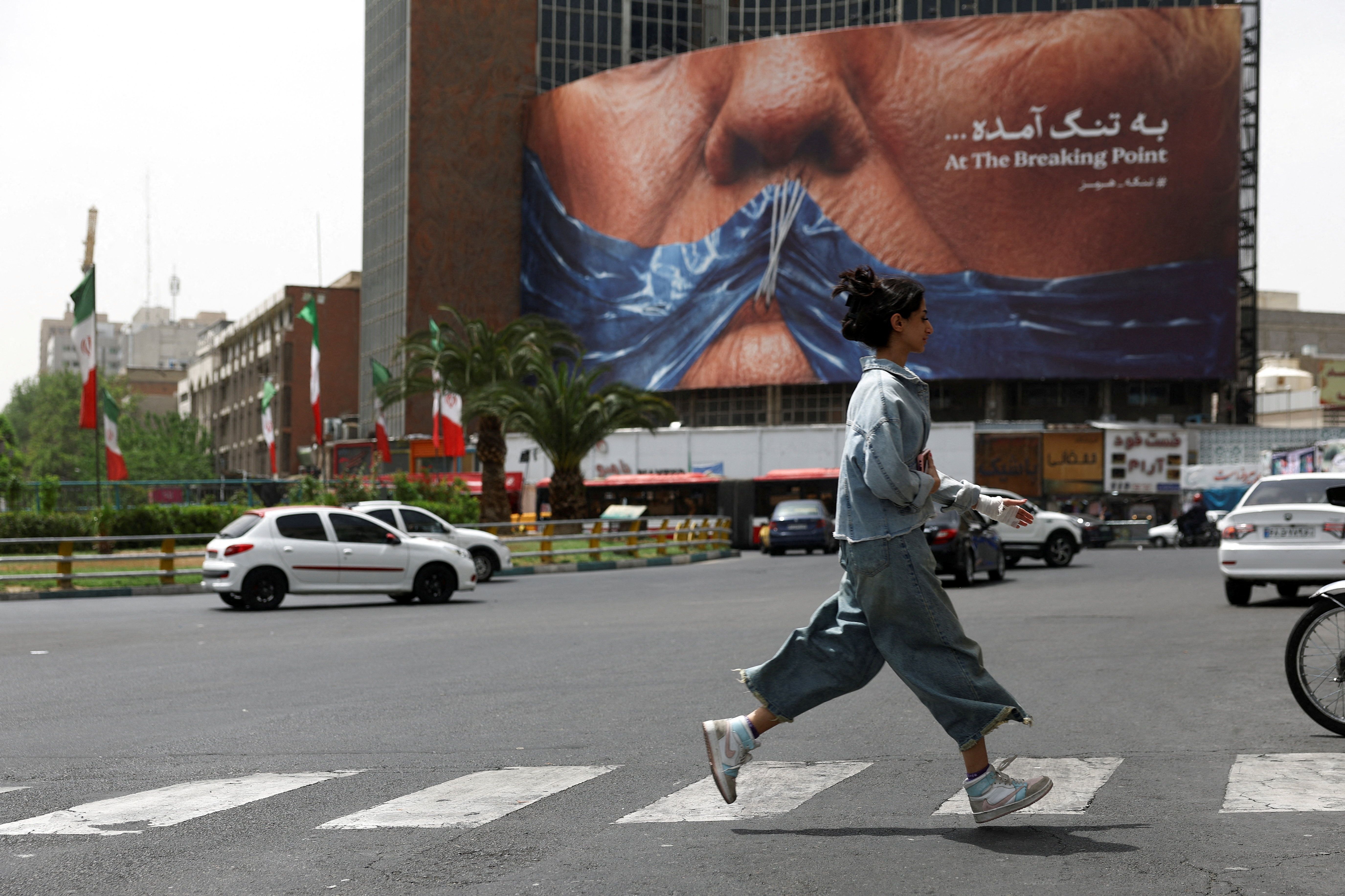 A woman walks past an anti-US billboard depicting US President Donald Trump and the Strait of Hormuz, in Tehran, Iran, May 4, 2026. 
