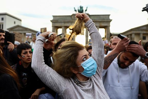 A demonstrator cuts hair during a protest following the death of Mahsa Amini, in front of the Brandenburg Gate in Berlin, September 23, 2022