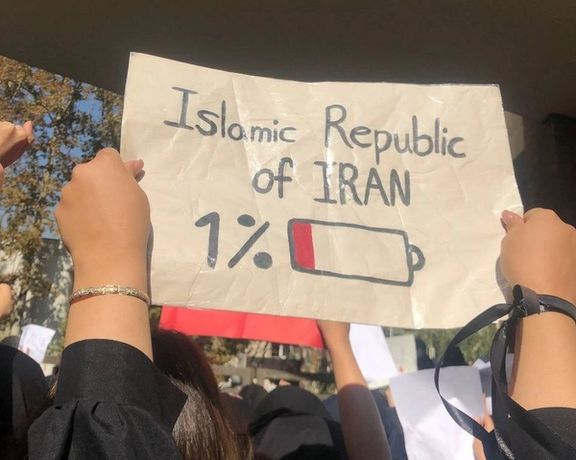 A university student holding up a sign that shows the Islamic Republic's "battery running low"