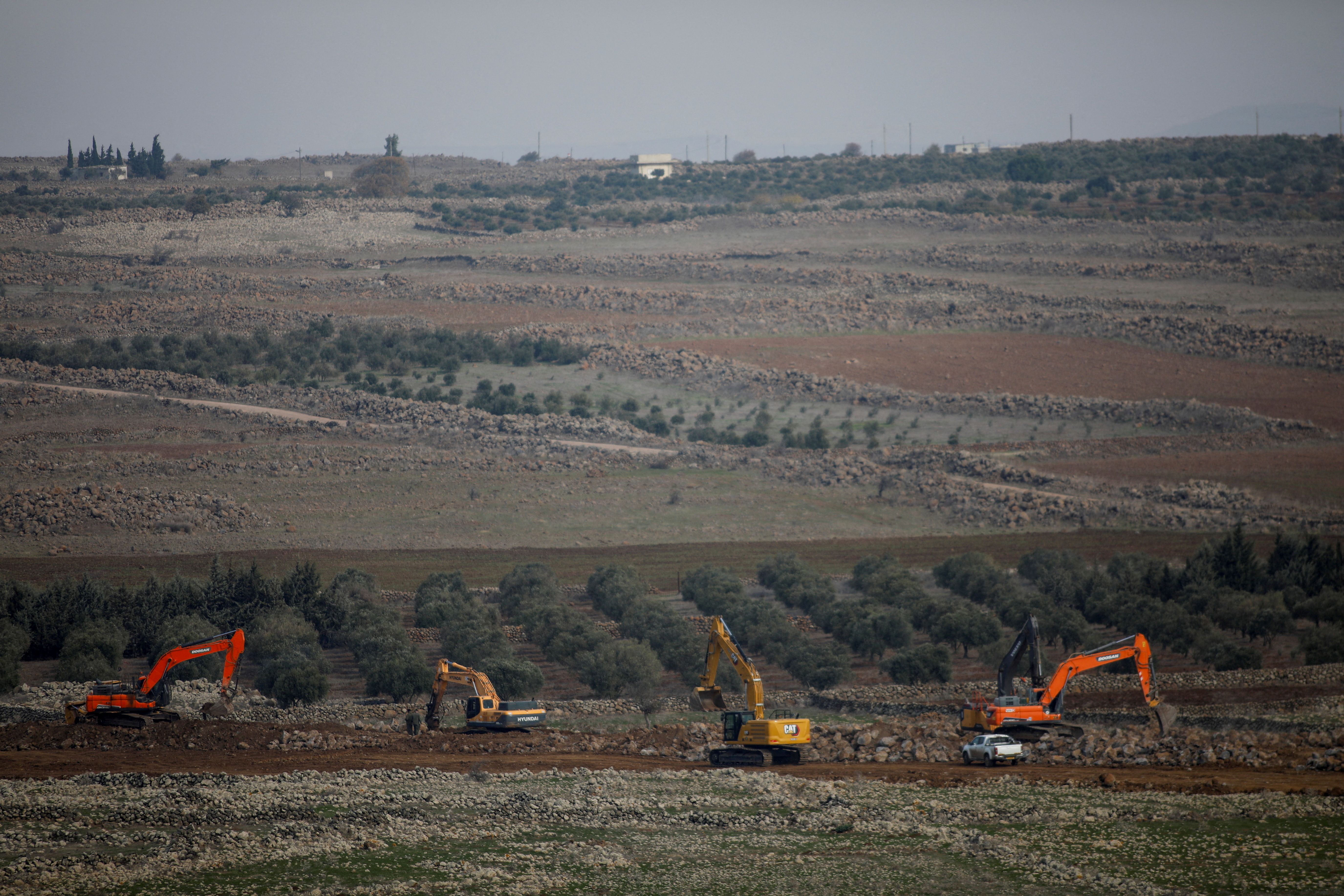 Workers use construction vehicles to build a barrier along the ceasefire border between Syria and the Israeli-occupied Golan Heights, December 8, 2024.